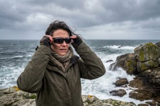 Femme portant des lunettes de protection UV sur la Côte d'Émeraude par temps de tempête automnale